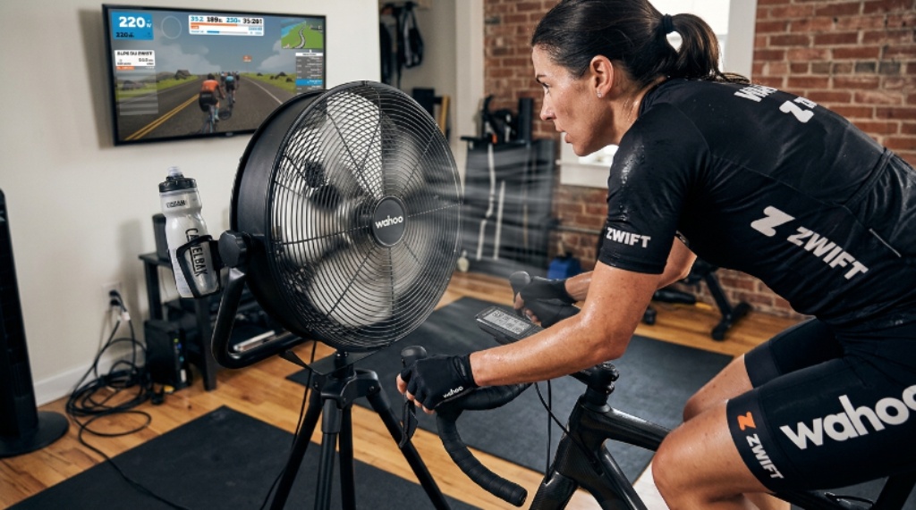 Close-up of an indoor cycling setup showing a high-velocity fan positioned at chest height in front of a stationary bike